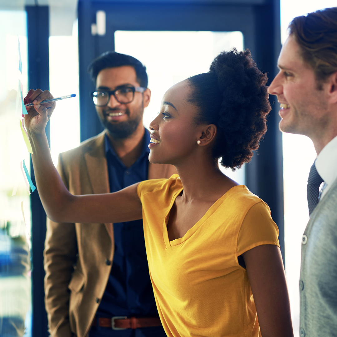 Women leading white board session with two male colleagues