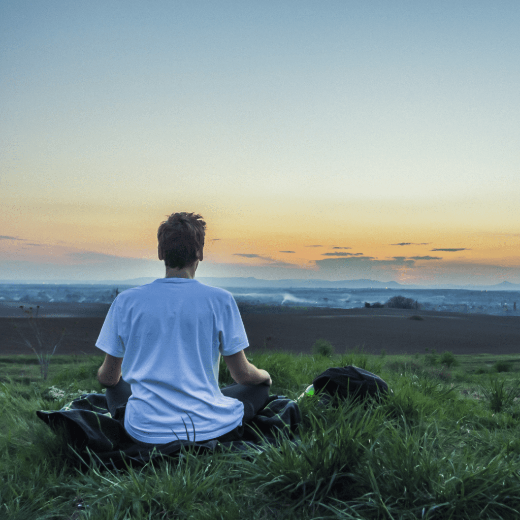 Man sitting in meditative position, looking a beautiful horizon.