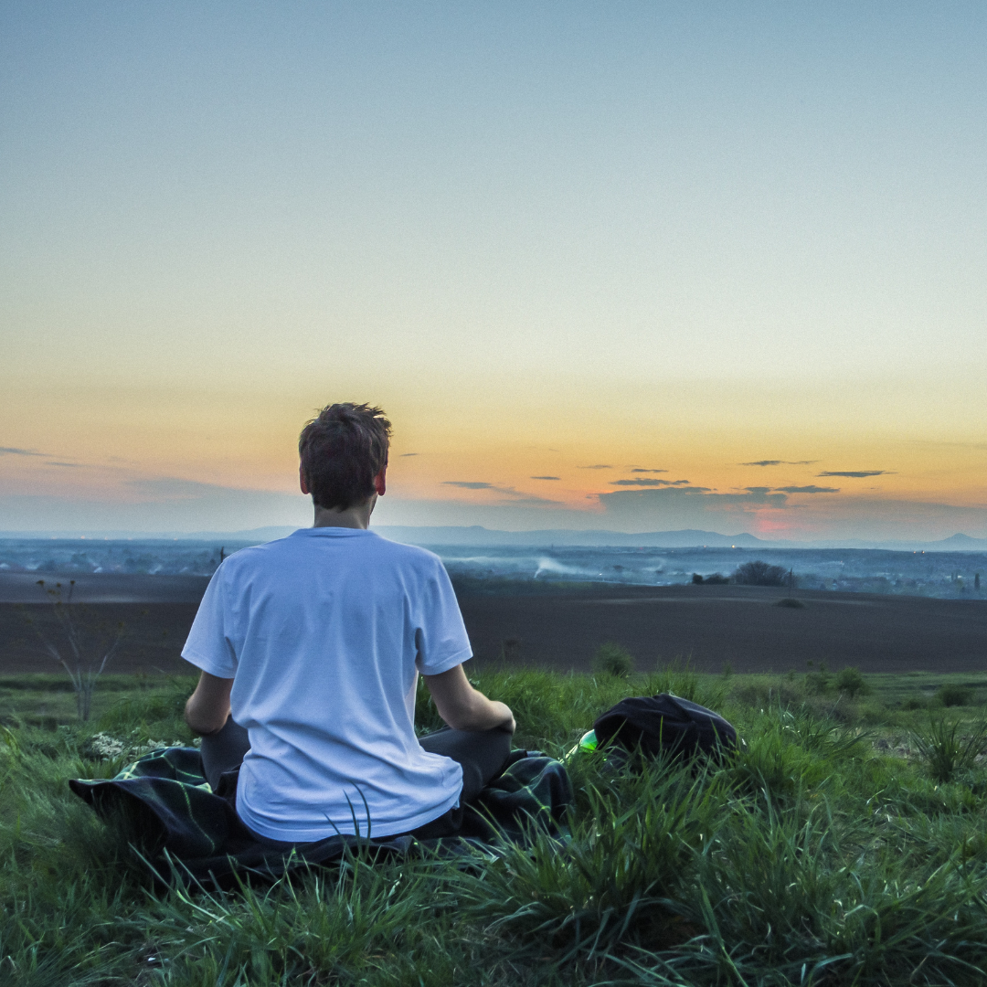 Man sitting in meditative position, looking a beautiful horizon.