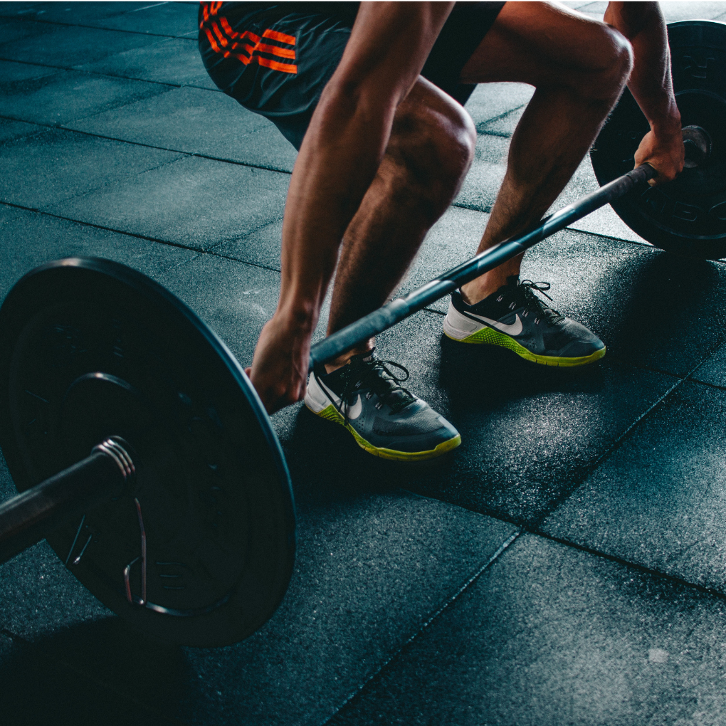 A man in dark shorts with red stripes about to perform a deadlift with very heavy weights.